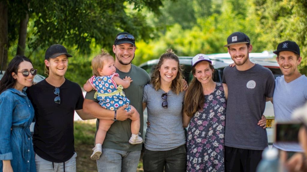 a group of adults and a baby having a group picture outdoors