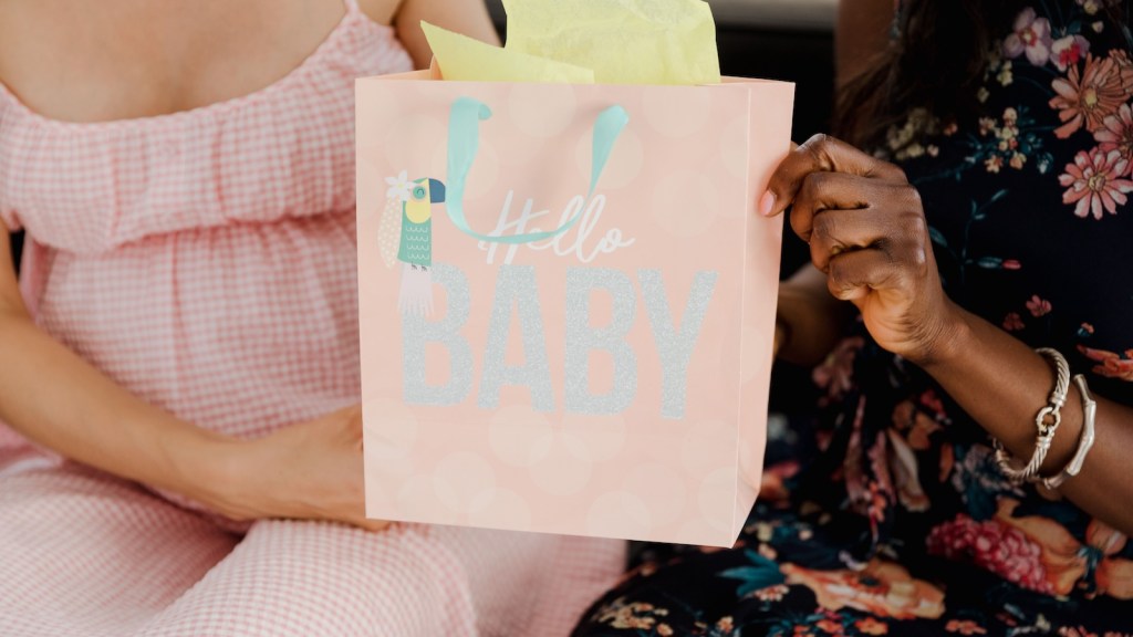 woman giving pregnant woman a baby shower gift bag