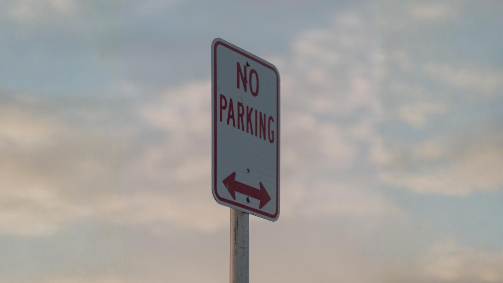Homeowner Traps Car Behind Private Gate After Repeated Parking Problems, Sparking Neighborhood Dispute closeup of a no parking sign
