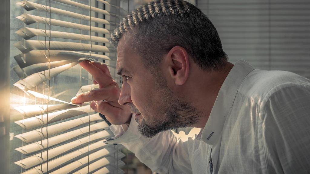 man looking through blinds