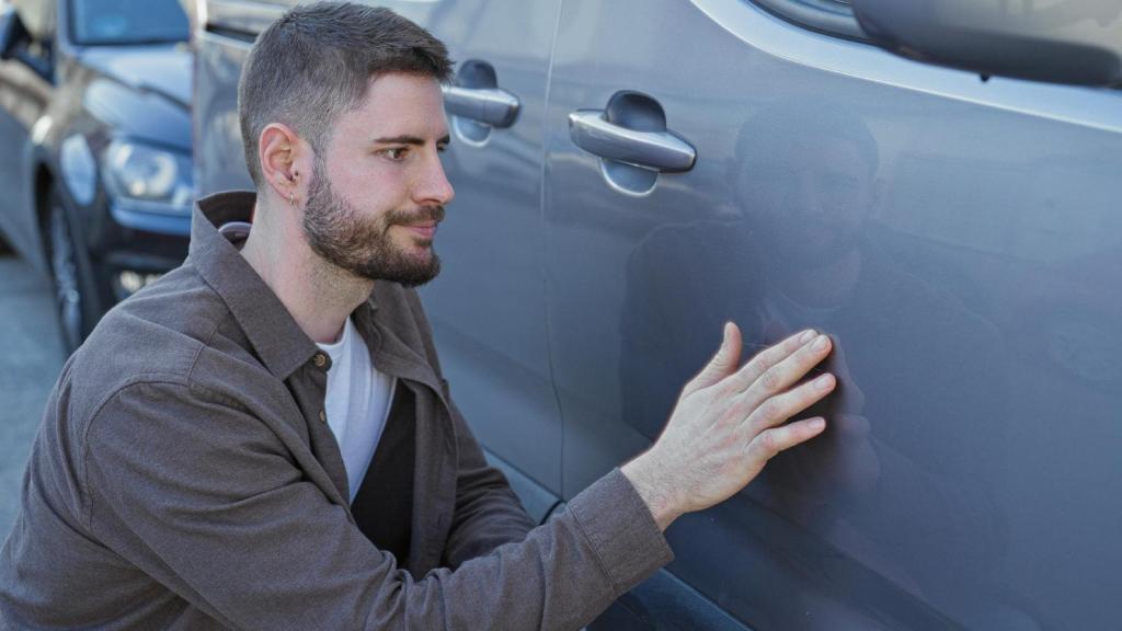 man looking at his car