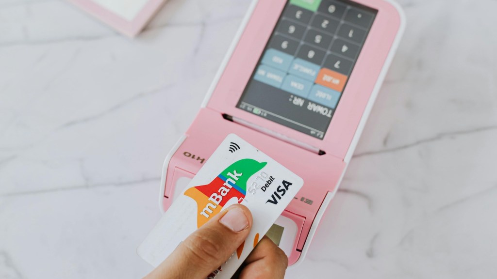 person paying on a pink atm with a credit card