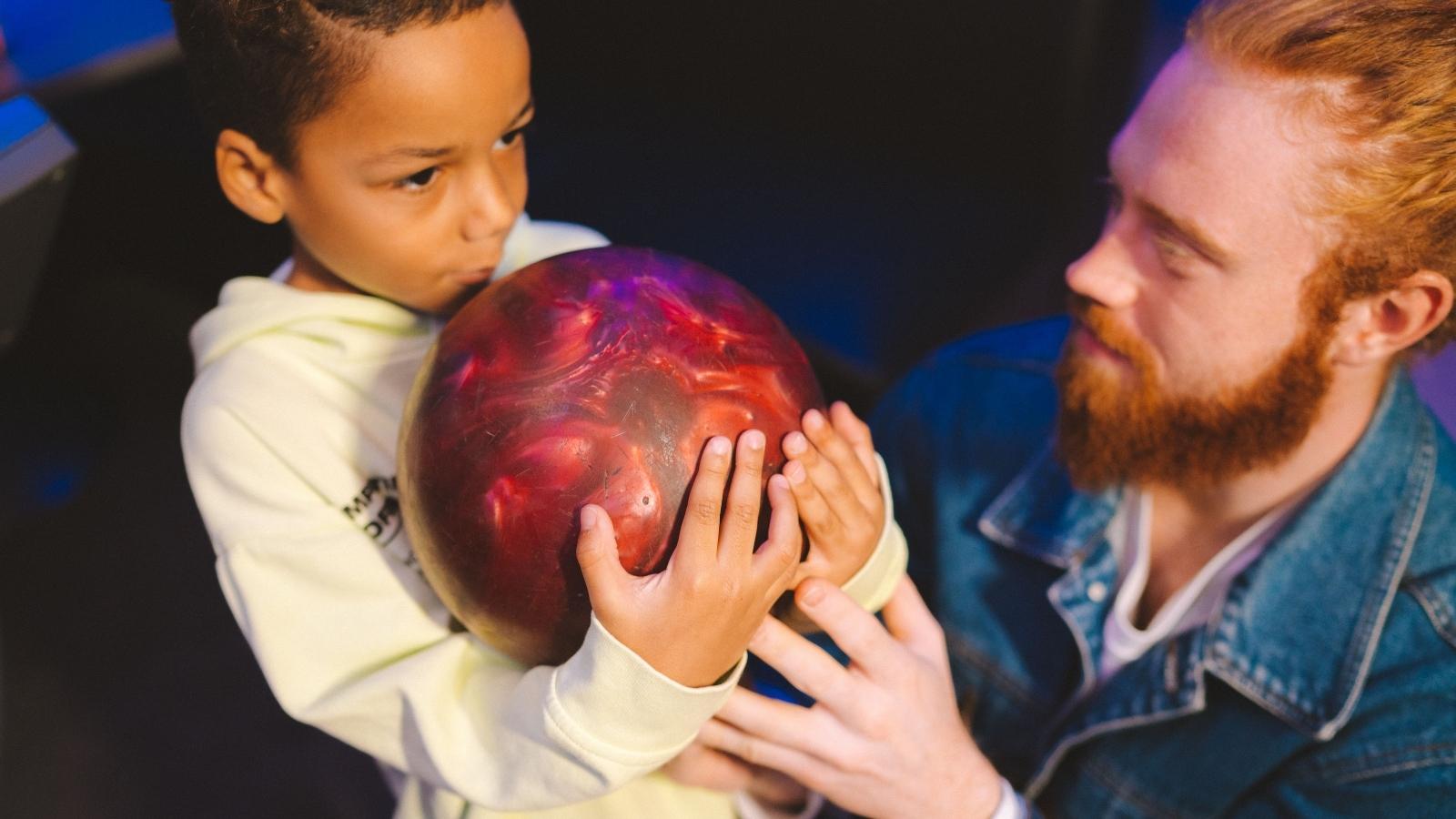 They Went Upstairs to Investigate a Sick Family Member’s Noise Complaint and Discovered the Neighbors Had Set Up a Real Bowling Alley kid holding a bowling ball