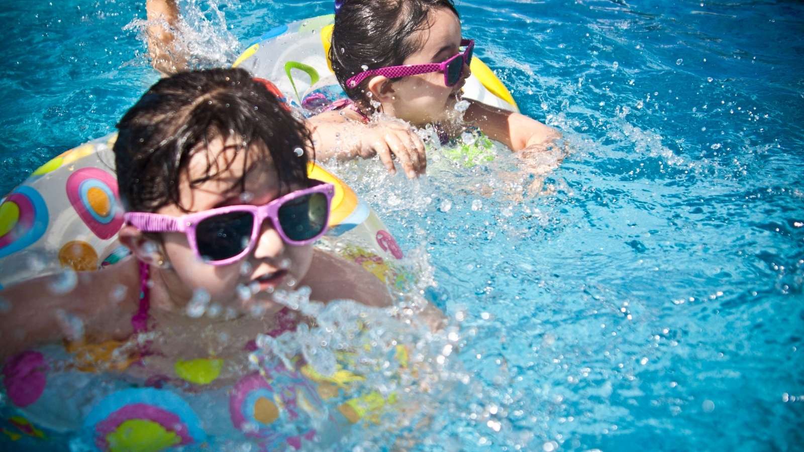 She Refused to Leave a Pool Full of Kids Unsupervised—Leading Her Husband to Label Her Stuck Up. kids in pink sunglasses and floaties swimming in pool