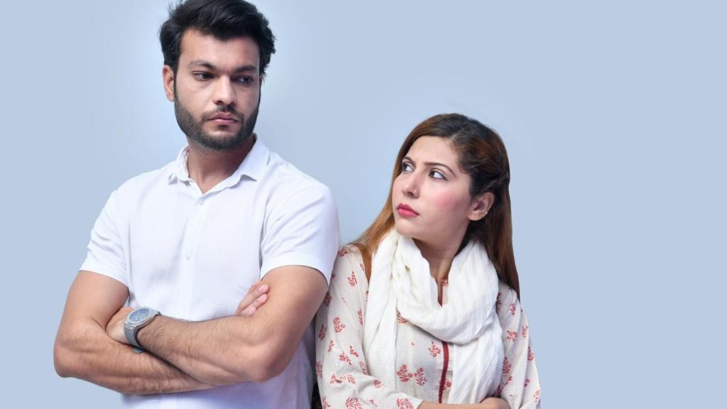 man and woman back to back looking upset