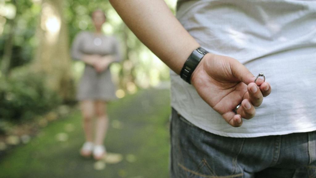 man holding an engagement ring behind his back