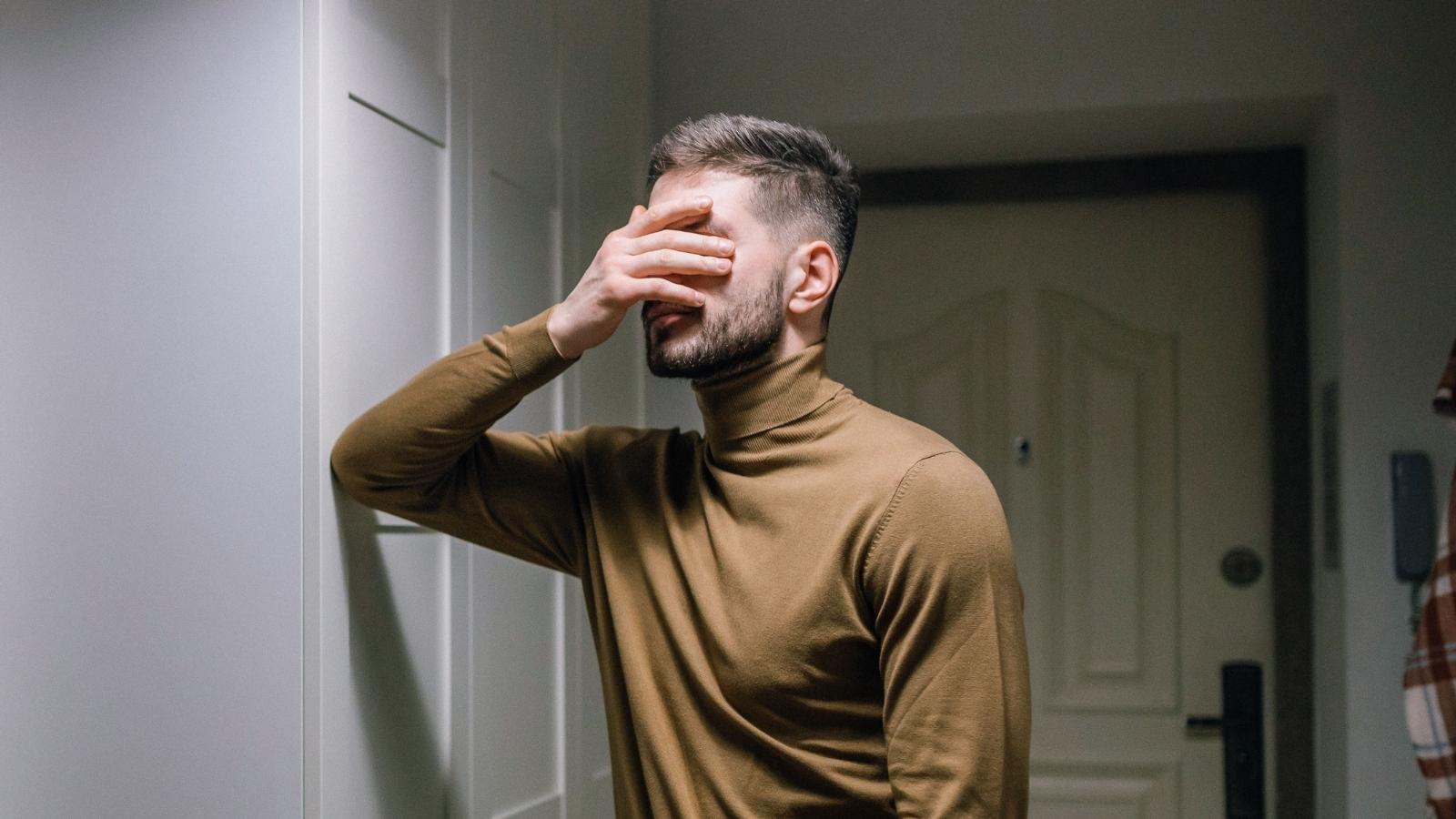 man in brown turtleneck facepalming