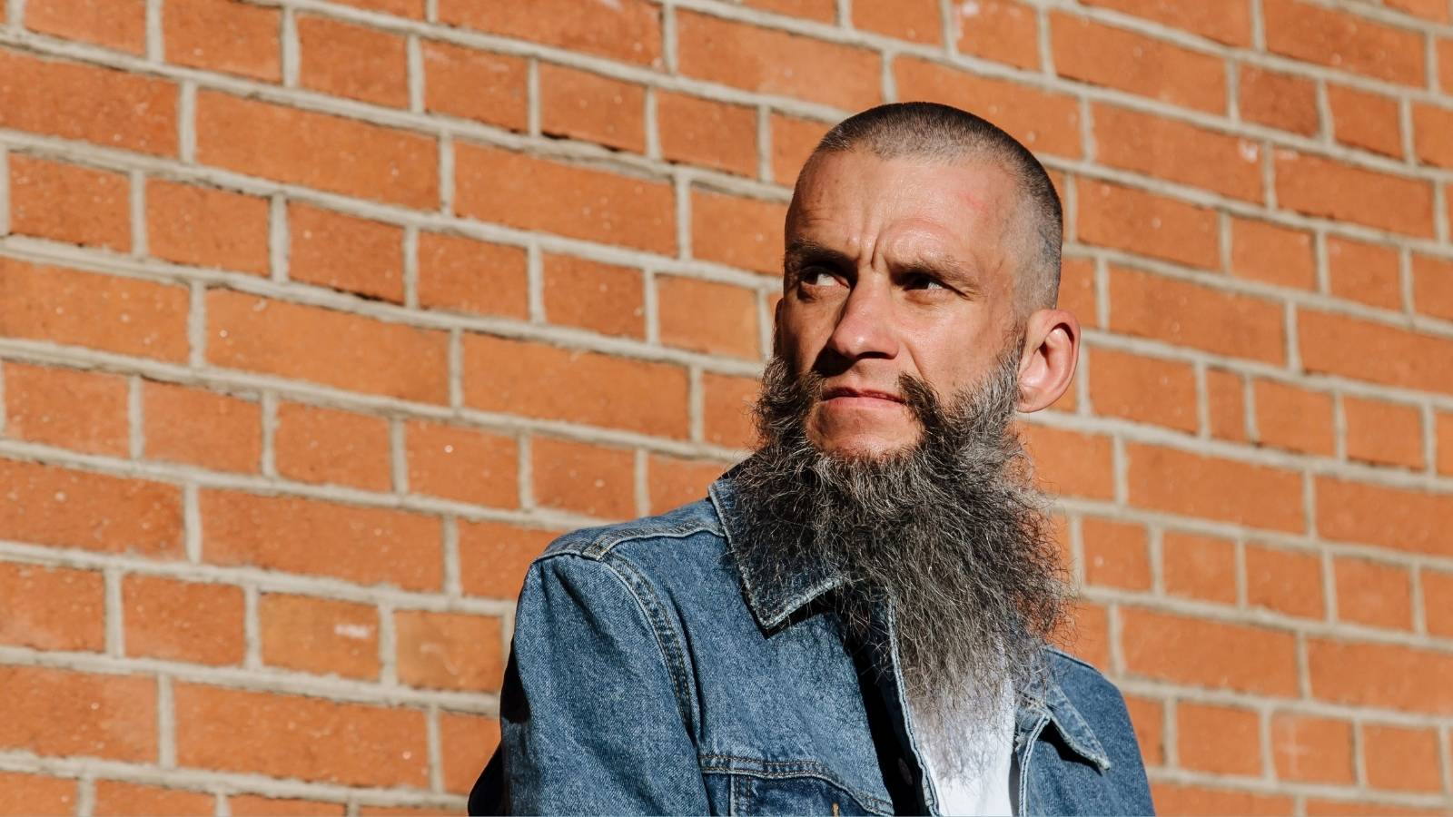 man with beard in front of brick wall