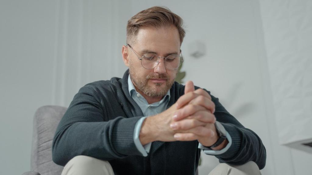 man with glasses with hands clasped