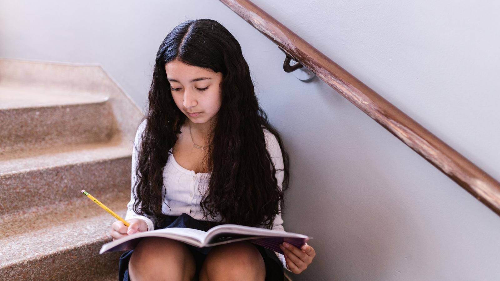 Middle Schooler Babysits Alone For Three Hours And Tells Her Mom She Can No Longer Help After Lack Of Support middle school girl doing homework on the stairs