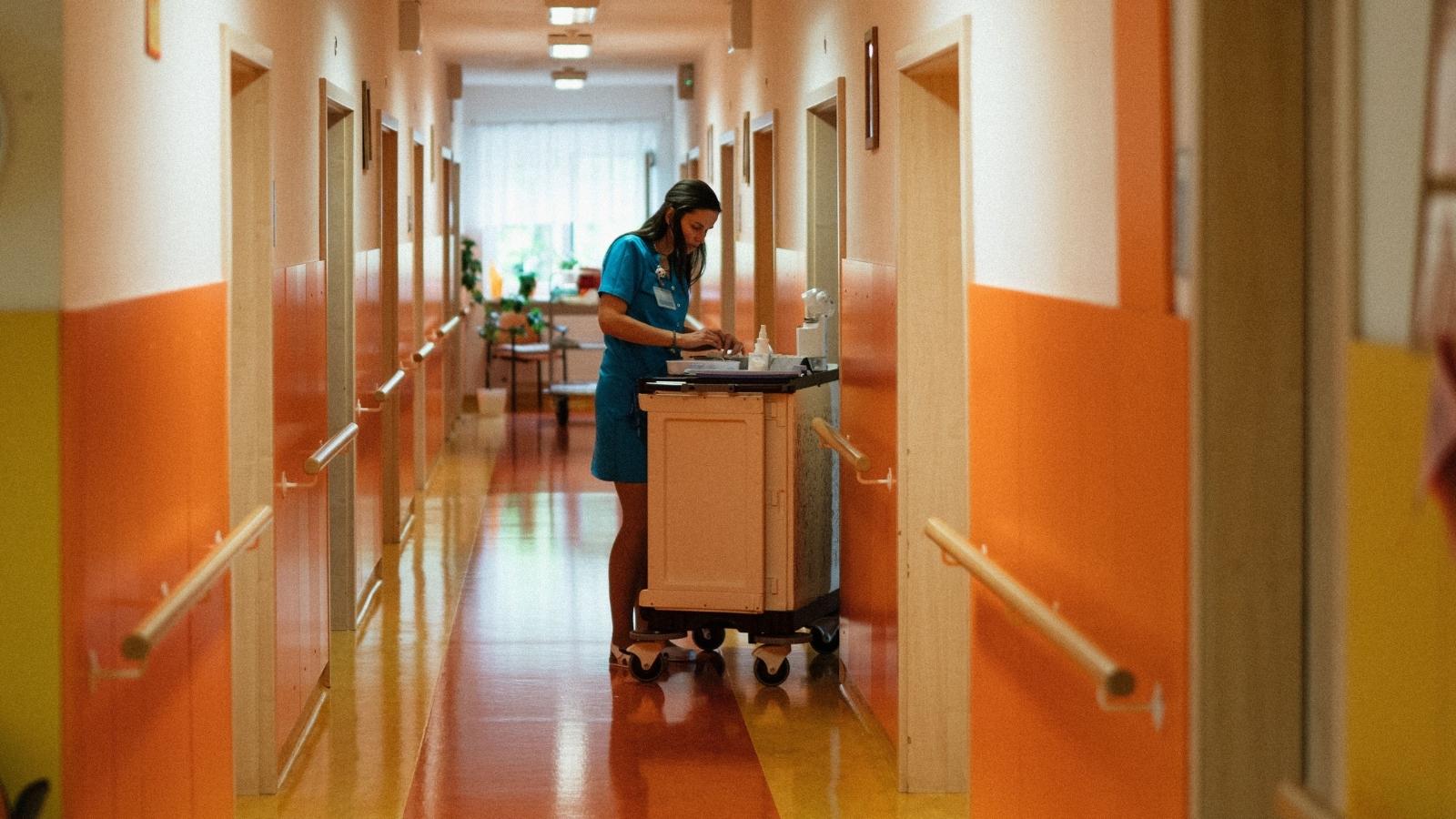 Nursing Home Worker Caught Napping Before Shift, Leading to a Workplace Policy Dispute nurse working in an orange hallway