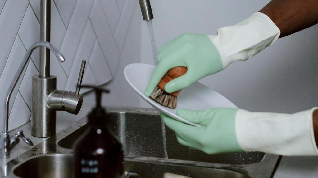 scrubbing dishes with green gloves