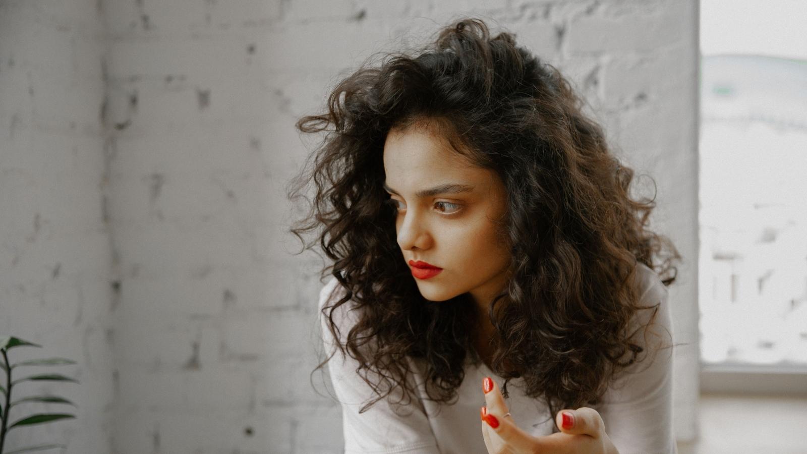 Woman Who Was Forced to Translate Her Whole Childhood Refuses to Do It for Her Entitled Husband side profile of an upset woman with curly hair