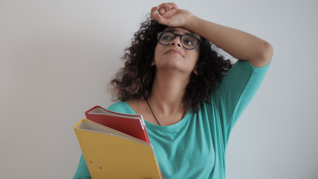 stressed woman holding stack of binders