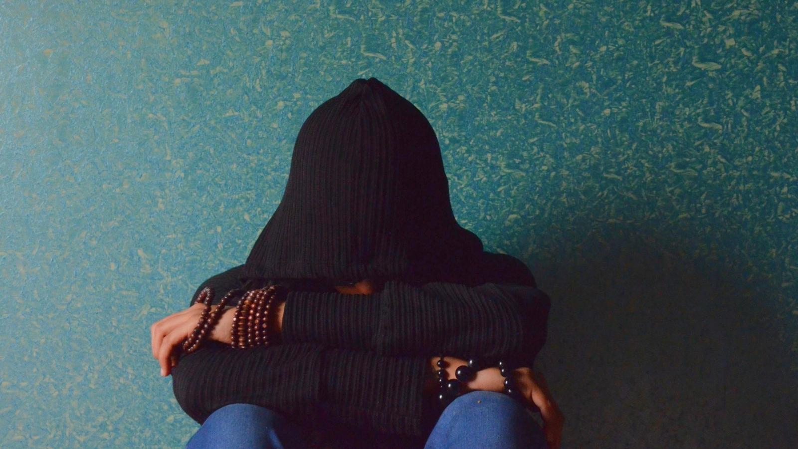 She Was Abandoned for Years. Then Her Mother Reappeared With the Ultimate Guilt Trip teenager sitting against the wall a dark hoodie