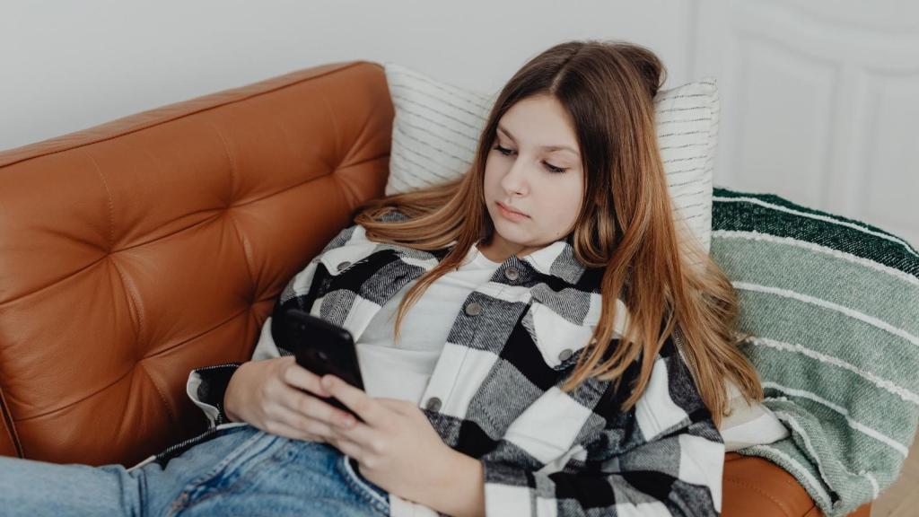 woman laying on the couch checking her phone
