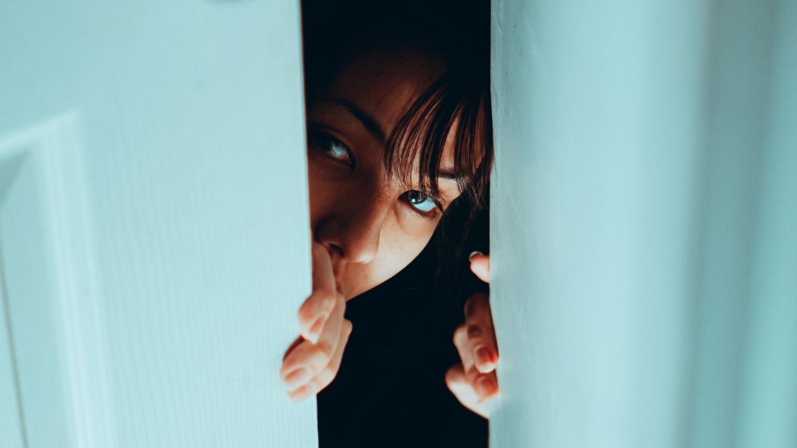 Young Woman Has Creepy Upstairs Neighbor Barge Into Her Apartment at 2 AM, Then He Returns Days Later Demanding She Move Out woman peeking through her door