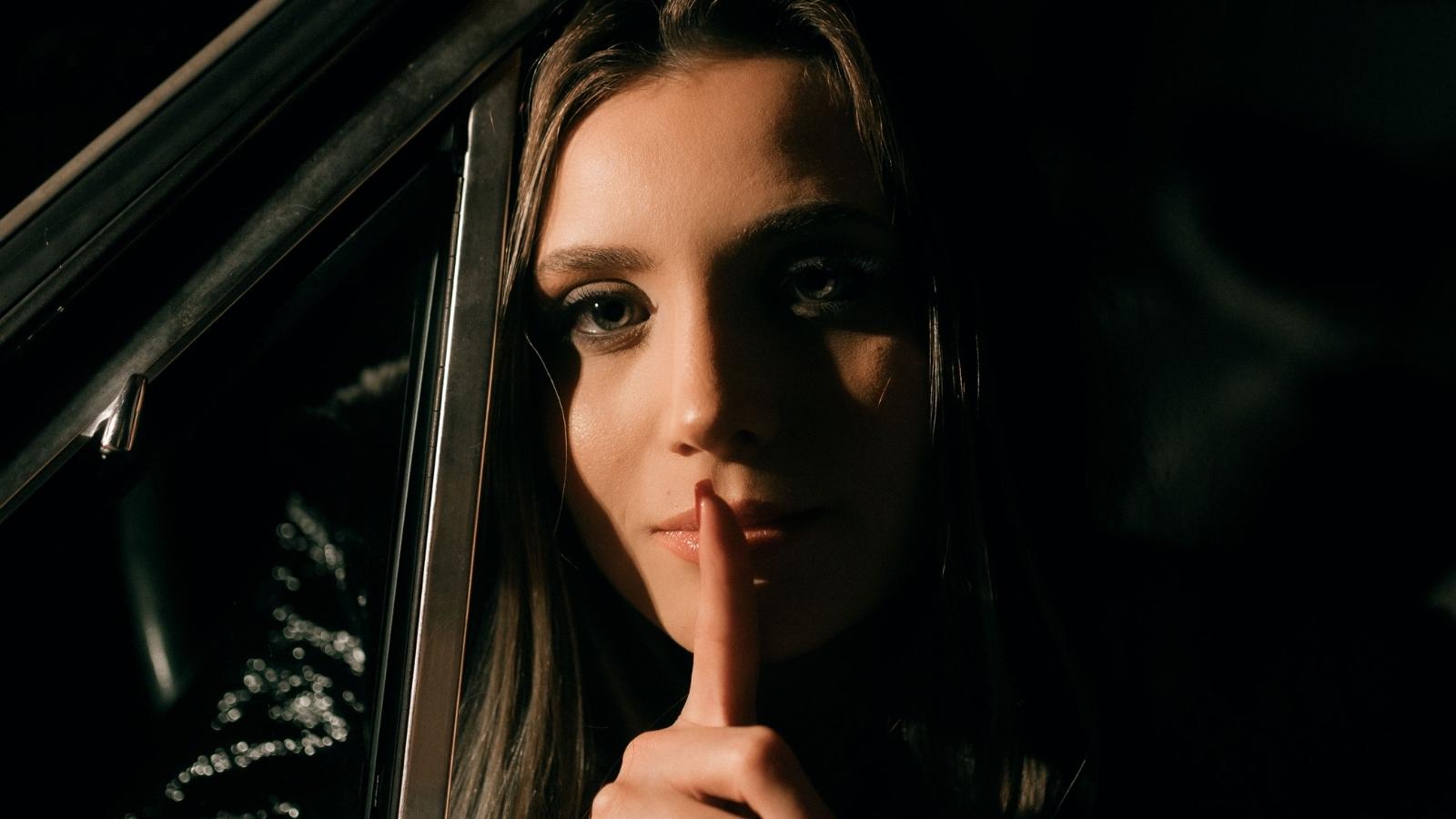She Watched Her Best Friend Steal Cash From Another Member of Their Circle. The Shocking Choice Splitting a Friendship Apart. woman putting finger up to mouth telling a secret