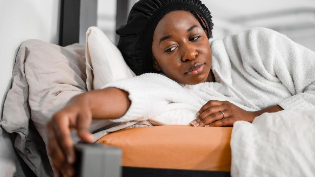 woman snoozing her alarm clock