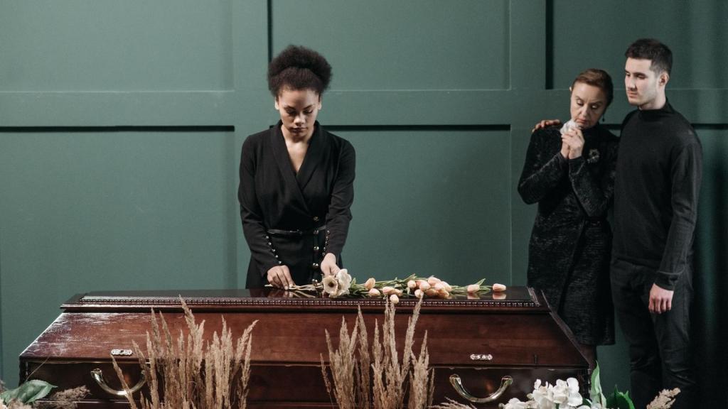 woman standing next to a funeral casket
