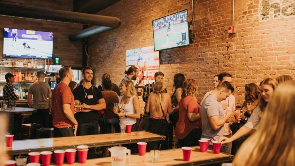 A crowded sports bar with people drinking, talking, and having a good time