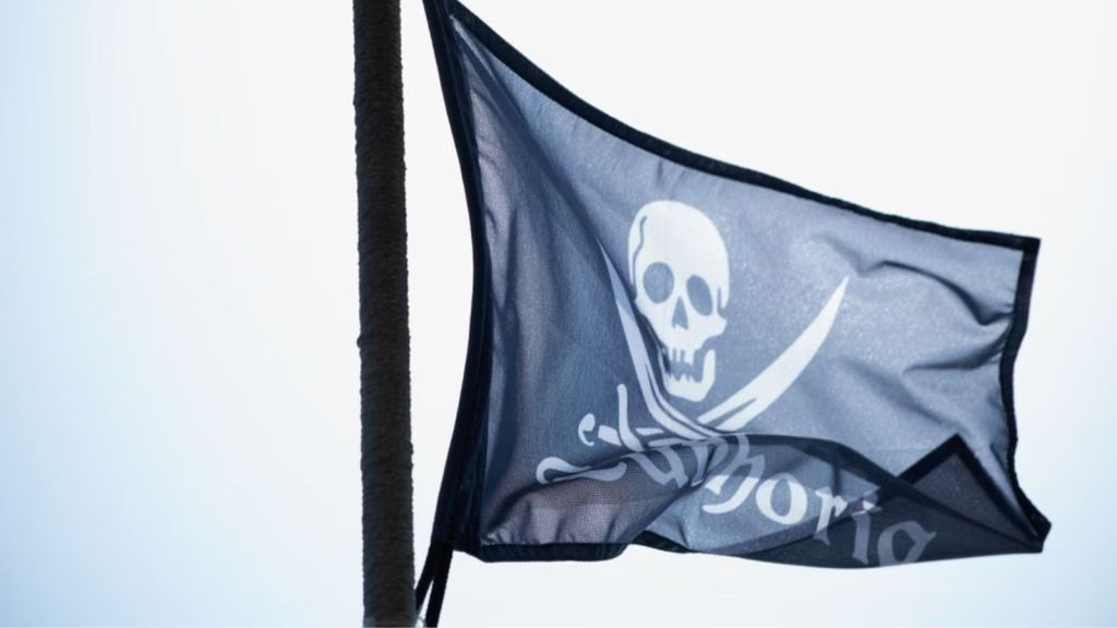 A pirate flag with skull waving against the sky