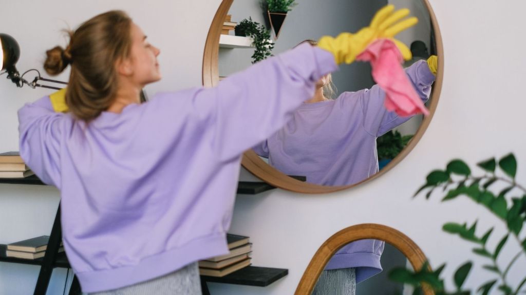 A woman cleaning a mirror
