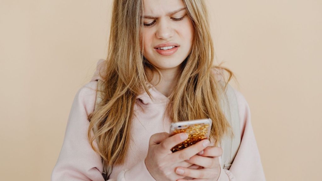 A girl grimacing at her phone