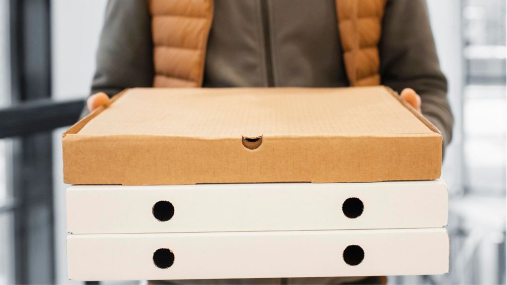 Delivery man holding three boxes of pizza