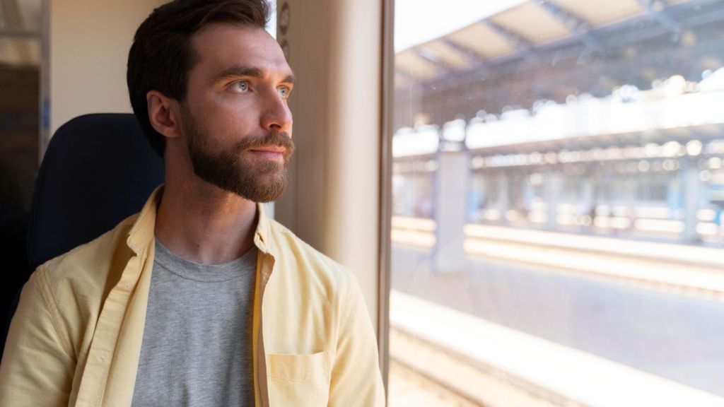 Man looking out the window while traveling on train