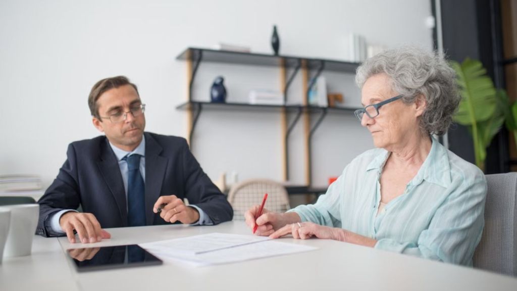 Old woman signing a document in front of an attorney