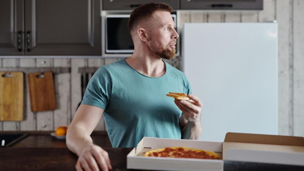 Man eating pizza he got from a local place