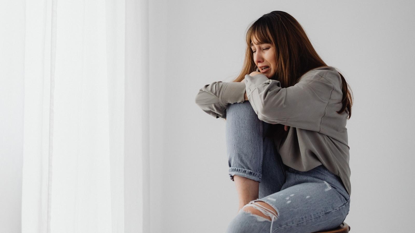 A Devoted Partner Is Reeling After Her Boyfriend Picked a Fight on Her Darkest Day Woman sitting on a chair crying alone