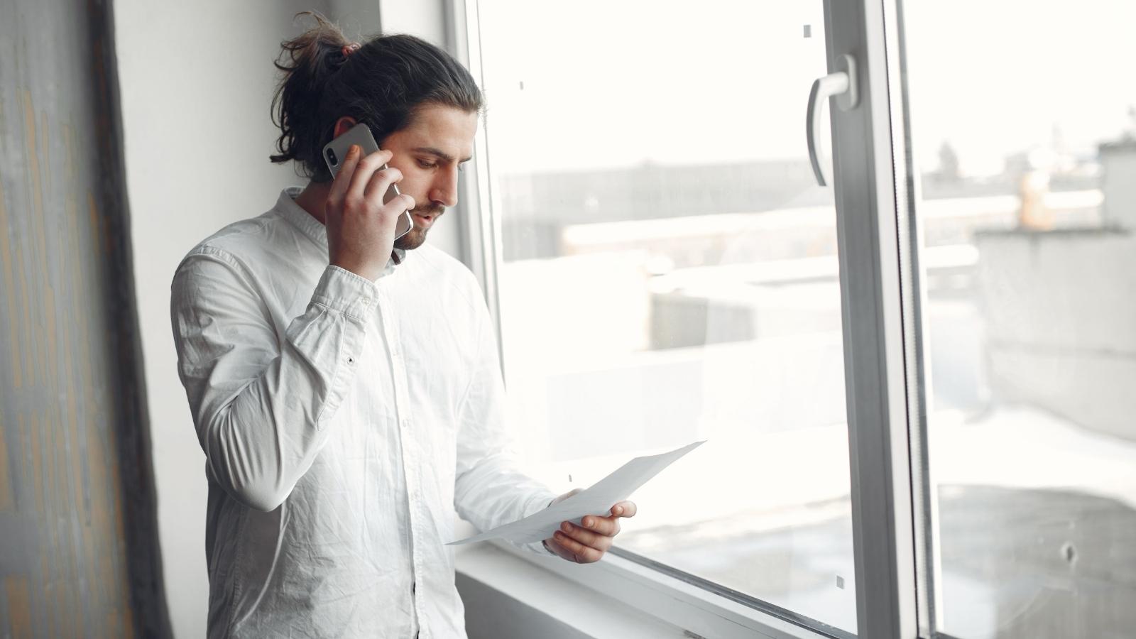 They Gave Their 60 Day Move Out Notice But a Lease Clause Says Termination Doesnt Take Effect Until End of Month, So Theyre Not Sure Which Applies Man standing by window looking at his lease