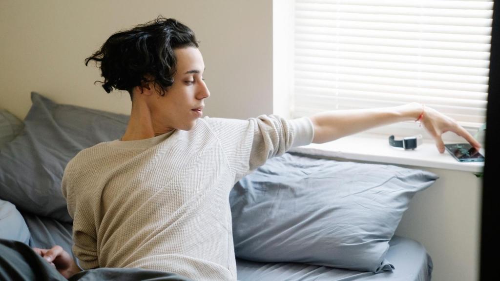 College student waking up and reaching for his phone