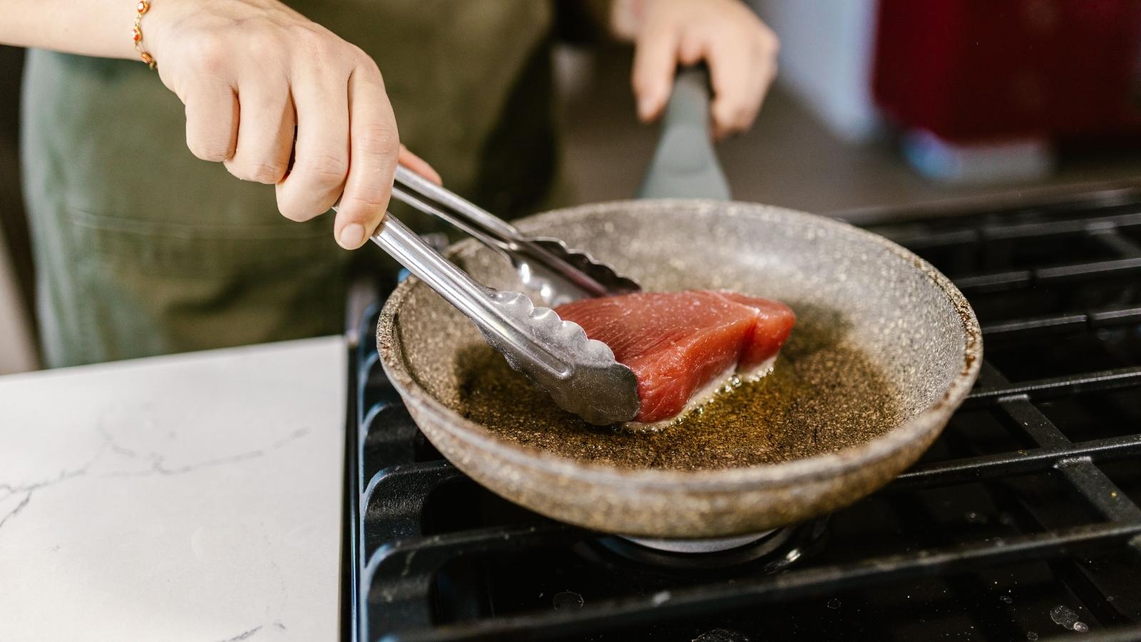Woman cooking salmon in a skillet