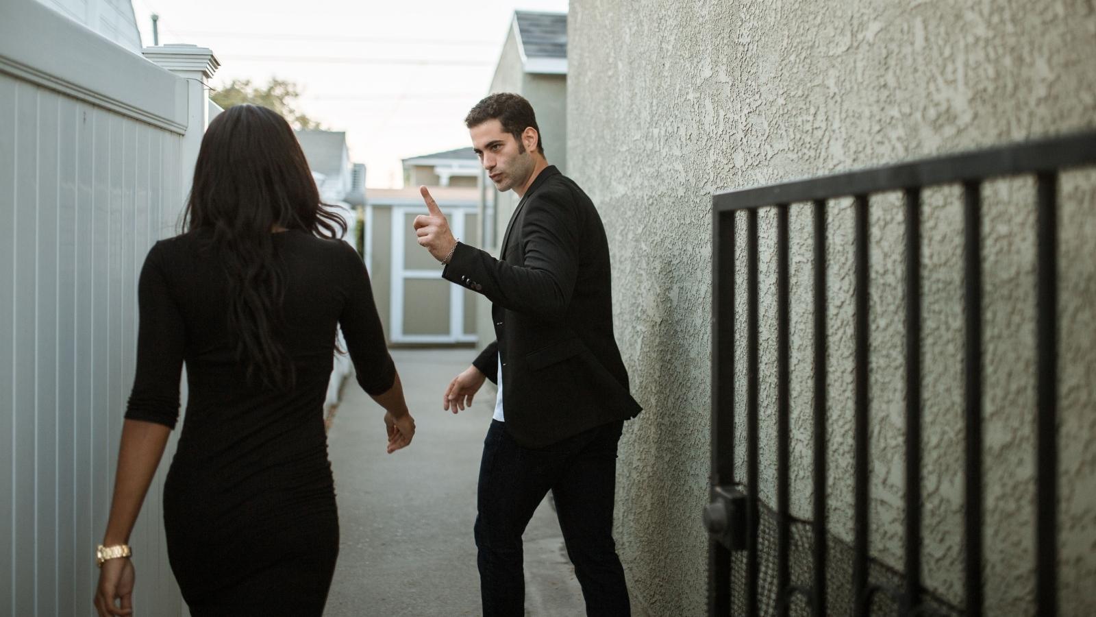 Man and woman fighting with each other outside.