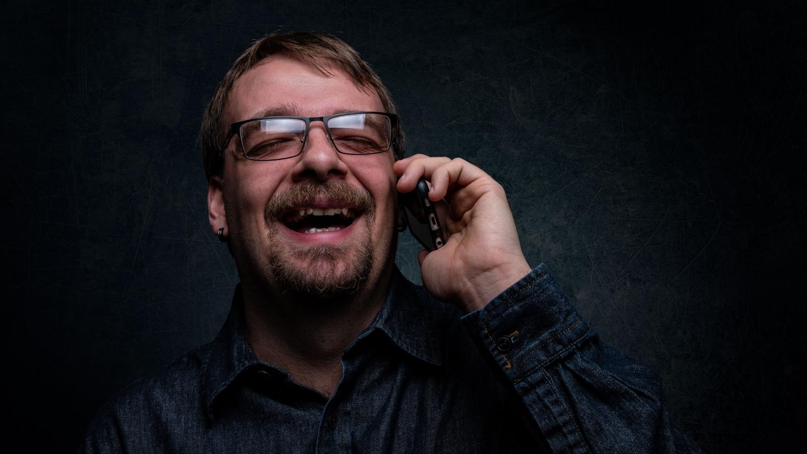 Marketing Employee Walks Away After Bereavement Leave Dispute Ends in HR Trouble Man laughing as he exposes someone on the phone