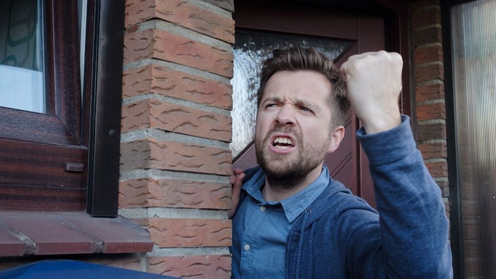 angry man yelling out his front door, fist in the air