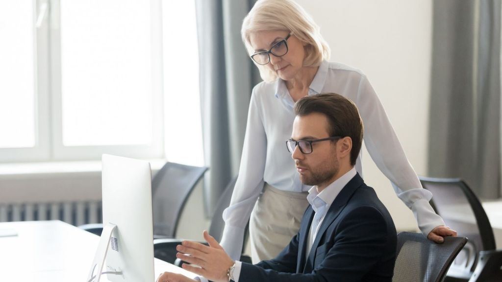 young man and older woman office workers looking at a computer
