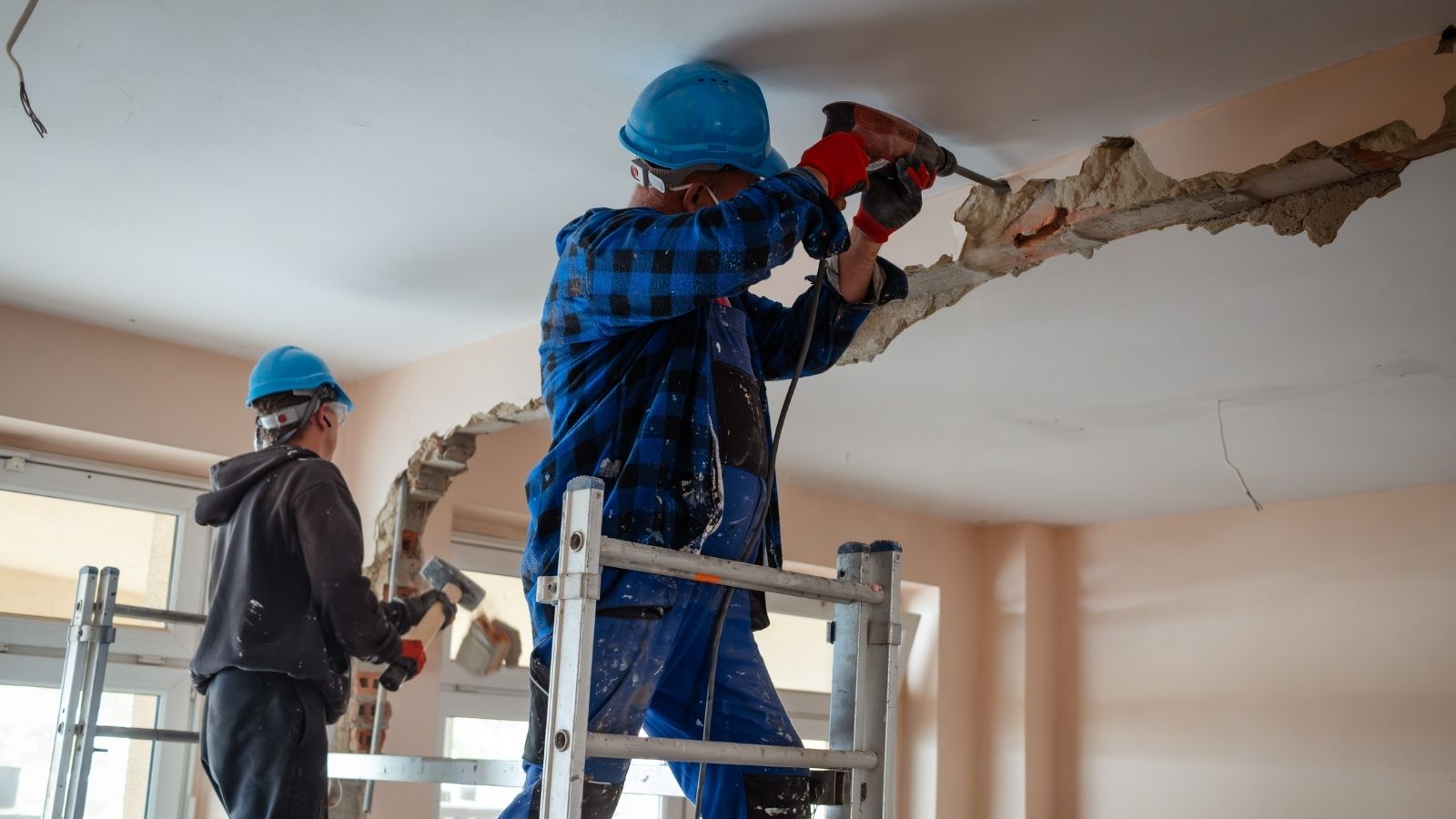 Family Buys Los Angeles Home to Tear It Down, Then Demolishes It Themselves Instead of Hiring a Crew two construction workers do demolition inside a house