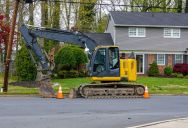 They Parked a Full-Sized Commercial Excavator in Their Front Yard. The Silent Legal Trap Neighbors Are Setting to Force It Off the Block.