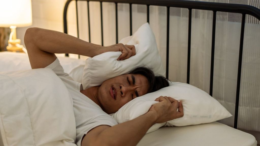 man trying to sleep through noise during the day