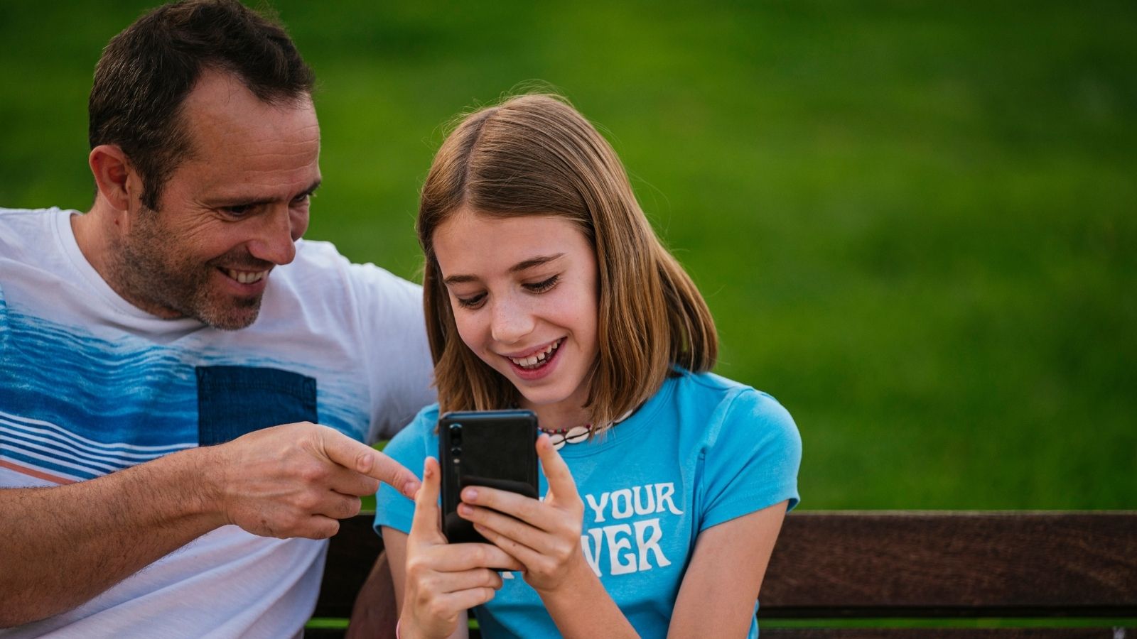 A Boy Tried to Embarrass Her Over Her Phone, But Instead, She Ended Up Bragging About Her Dad little girl and dad looking at a phone outside