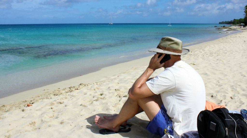 man sitting on the beach talking on the phone