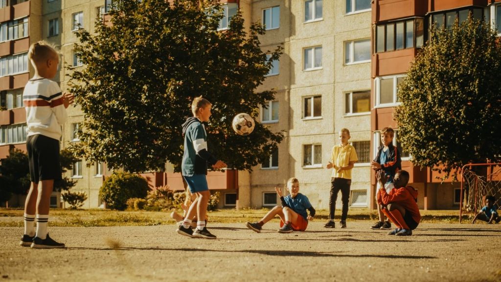 kids playing soccer outside an apartment building