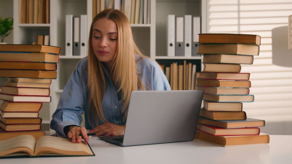 young woman studying while surrounded by books