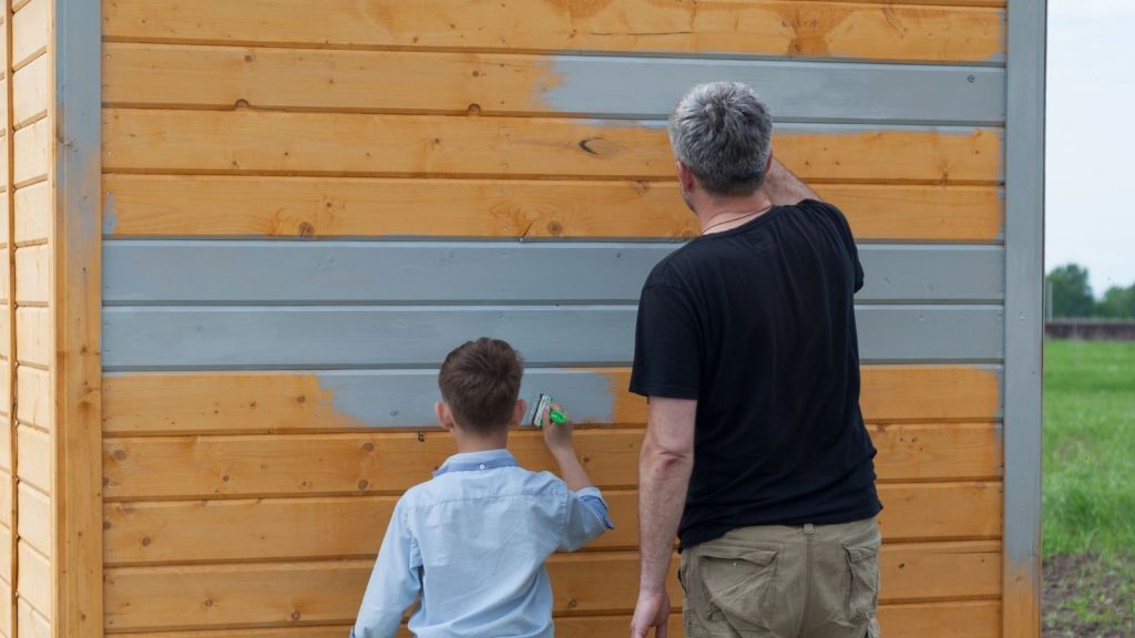 father and son painting a wooden shed grey