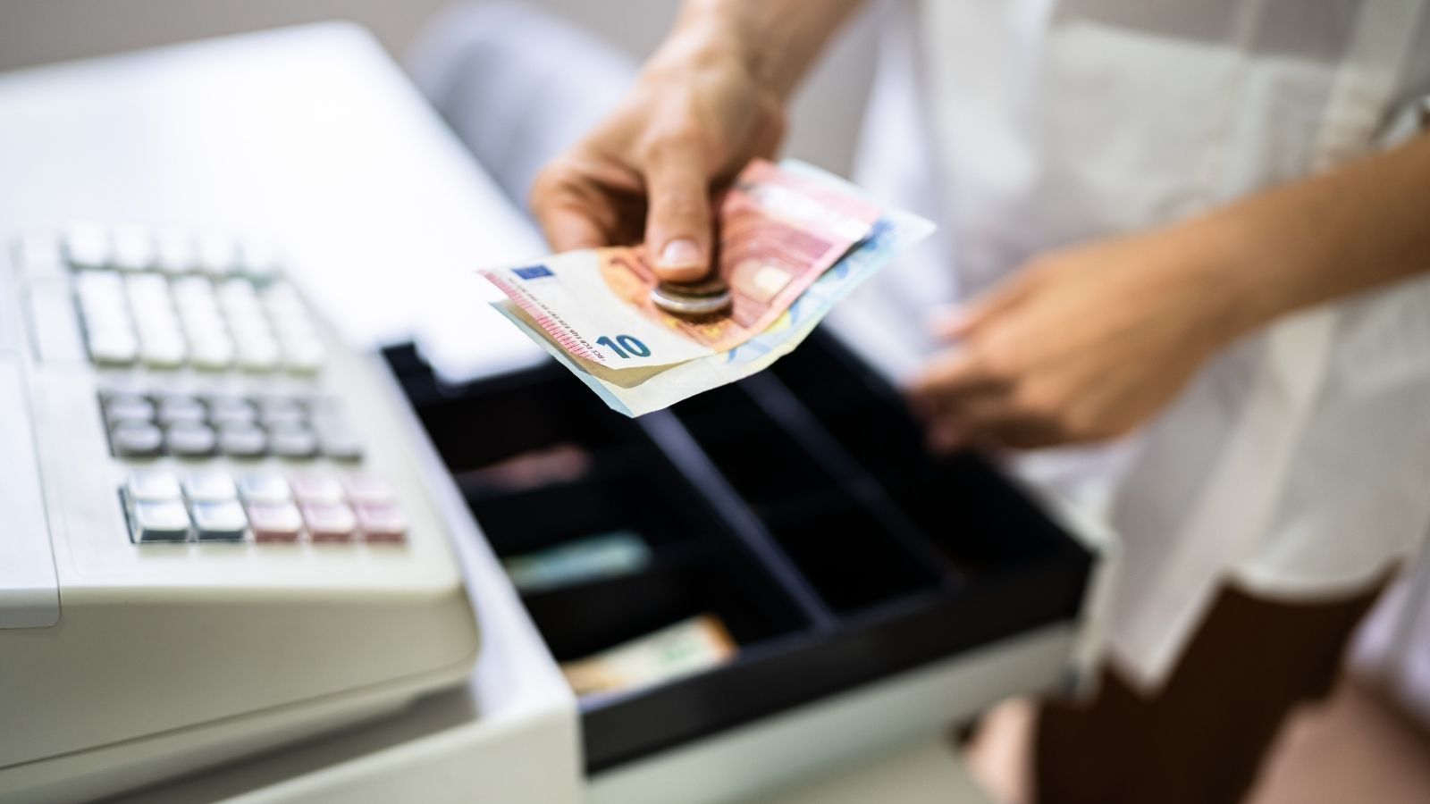 She Tried Paying for Groceries With as Much Change as Possible—But the Store Had a Rule cashier putting cash payment in cash register