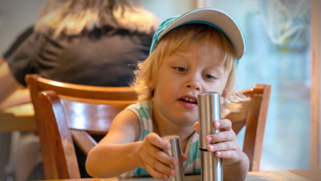 little boy playing with salt and pepper shakers at a restaurant